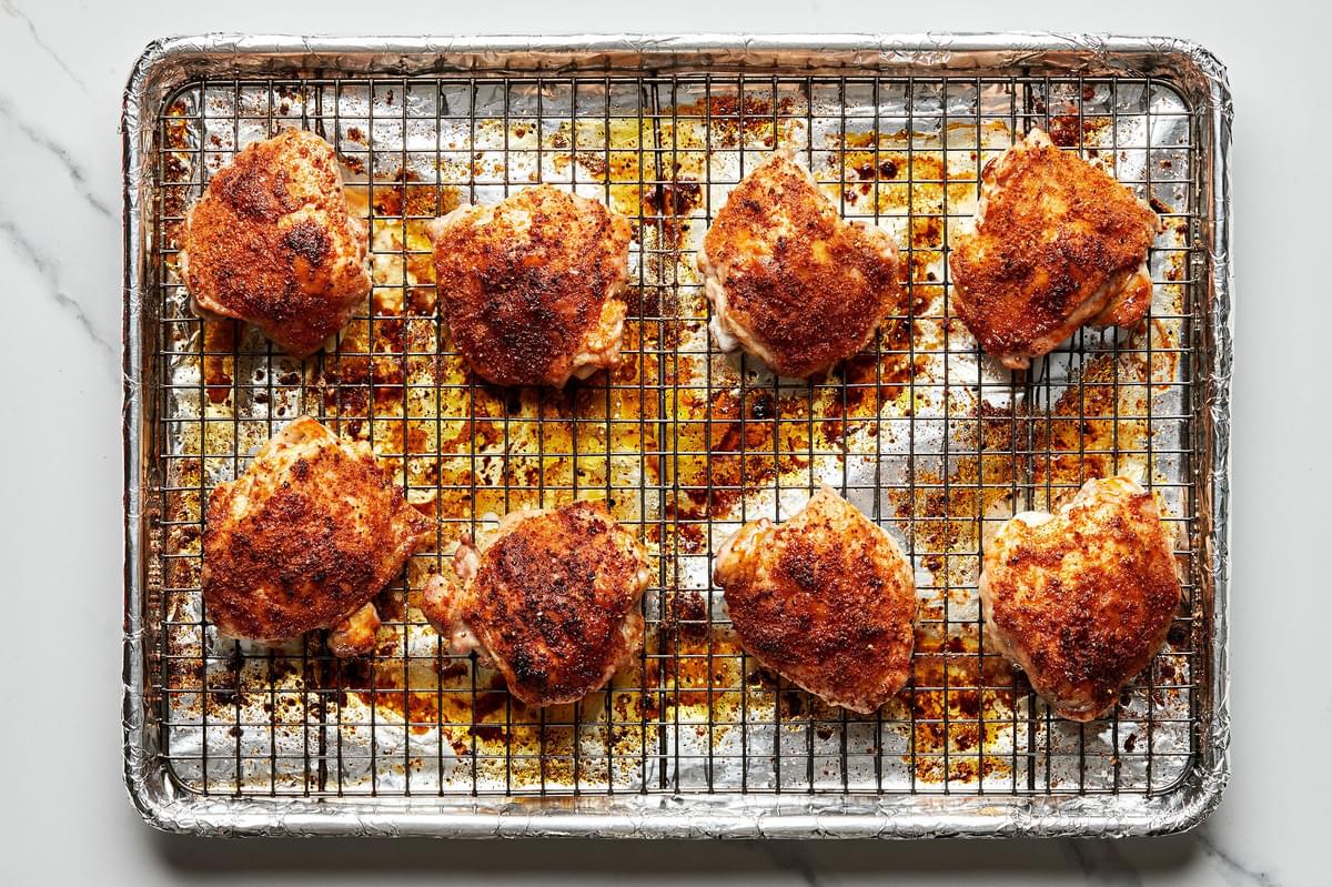 oven baked chicken thighs on a cooling rack place don top of a foil lined baking sheet
