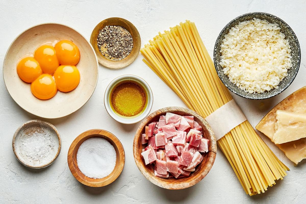 spaghetti, egg yolks, Pecorino Romano, salt, pepper, olive oil  and guanciale in bowls to make homemade pasta carbonara