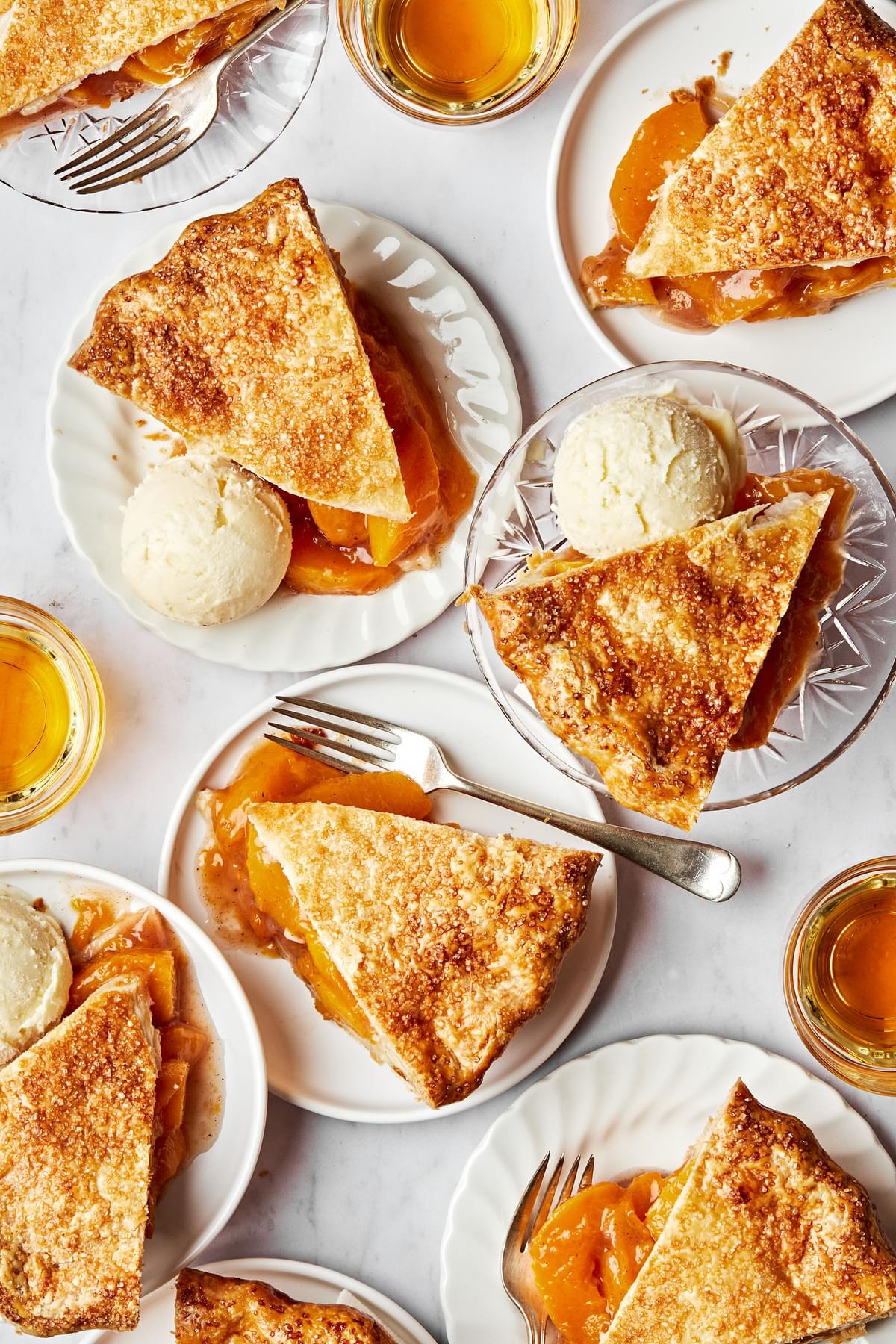 slices of homemade peach pie on plates served with scoops of vanilla ice cream