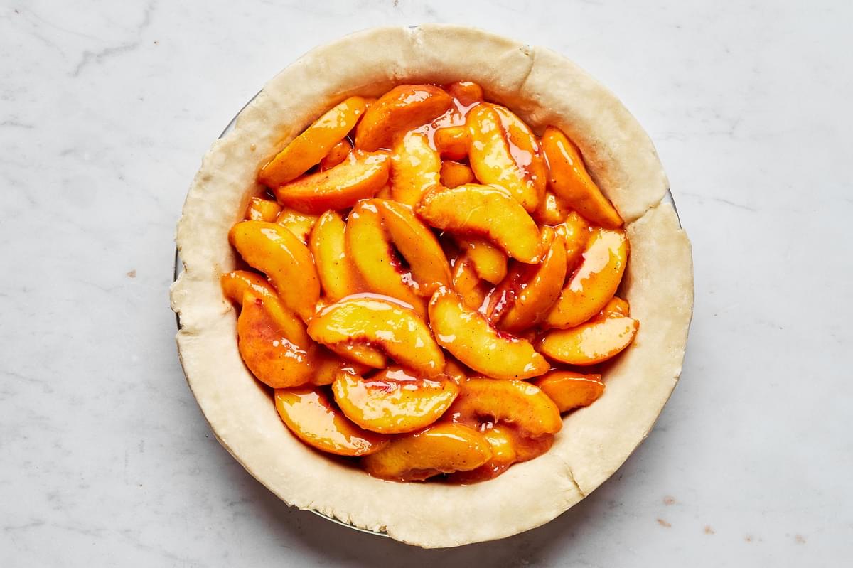 homemade pie crust in a pie pan filled with peaches