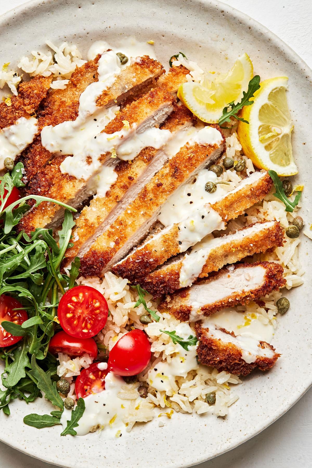 pork milanese bowls made of Skillet-Fried Pork Cutlets on top of lemon parmesan rice  and drizzled with creamy lemon dressing