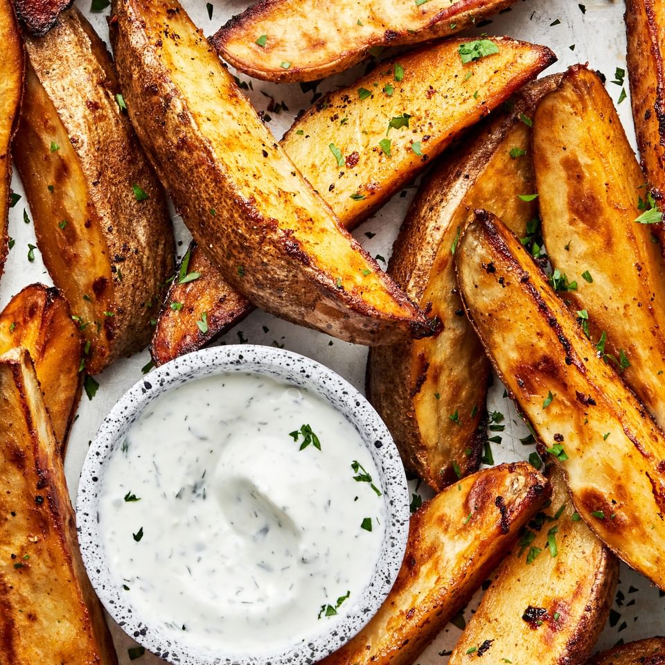homemade Potato Wedges seasoned with brown sugar, salt, pepper, garlic powder and paprika served with a cup of Ranch dressing