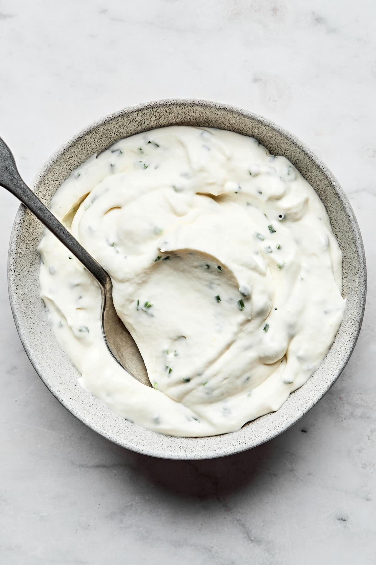 horseradish sauce in a bowl with a spoon made with heavy whipping cream, sour cream, mayo, horseradish, chives and salt