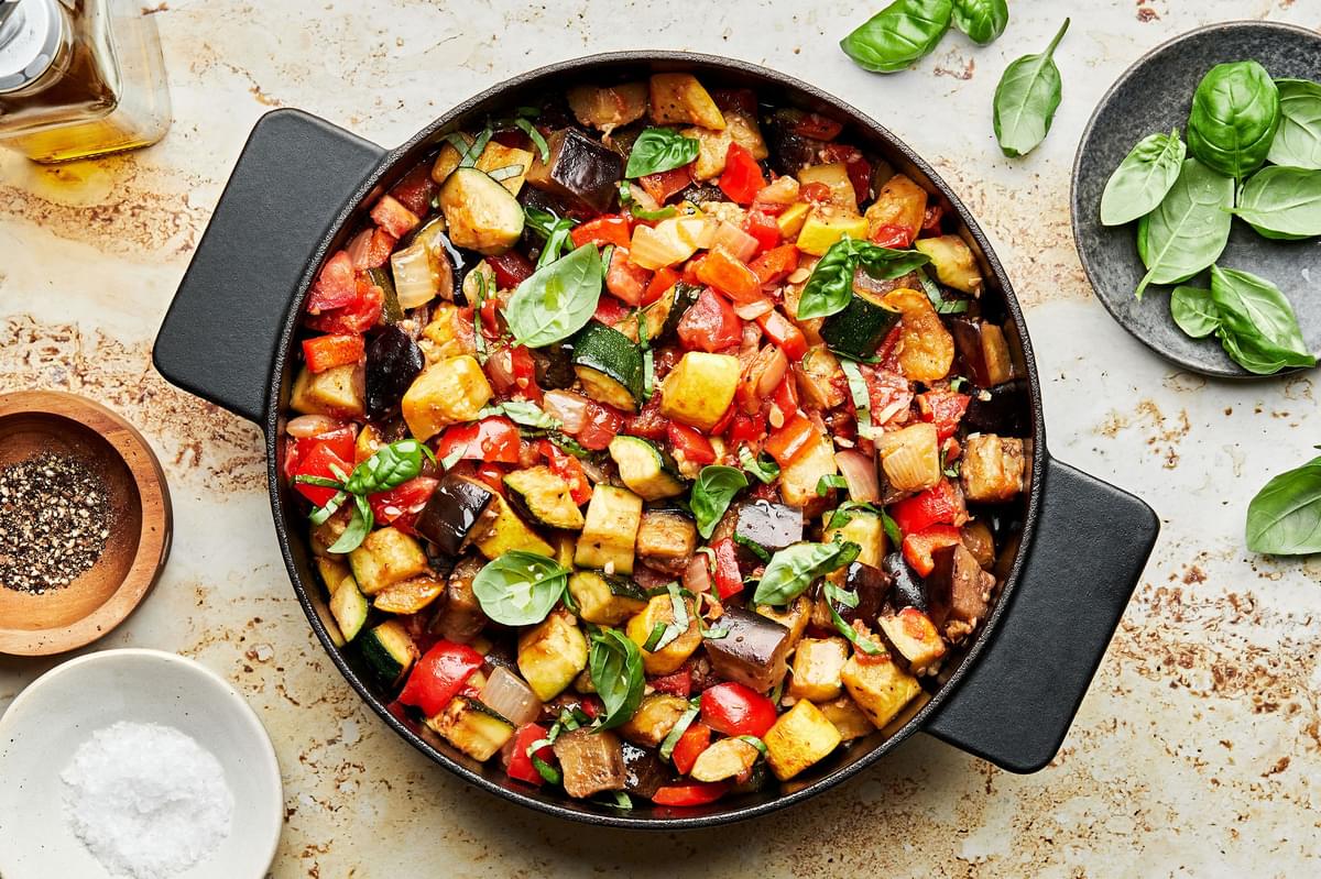homemade ratatouille in a skillet made with eggplant, zucchini, squash, onion, garlic, thyme, tomatoes, bell peppers & basil