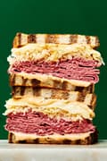a stacked reuben sandwich made with rye bread pastrami, sauerkraut, Swiss cheese & Russian  style dressing