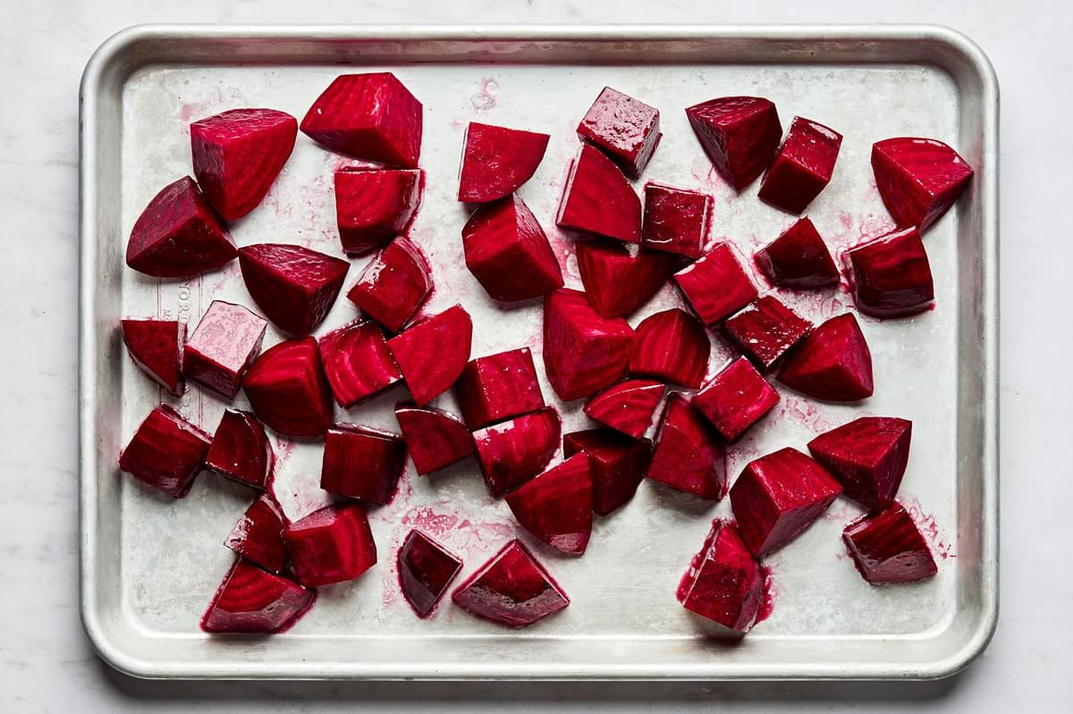 raw beets peeled and chopped on a baking sheet tossed with olive oil and salt ready to be roasted in the oven
