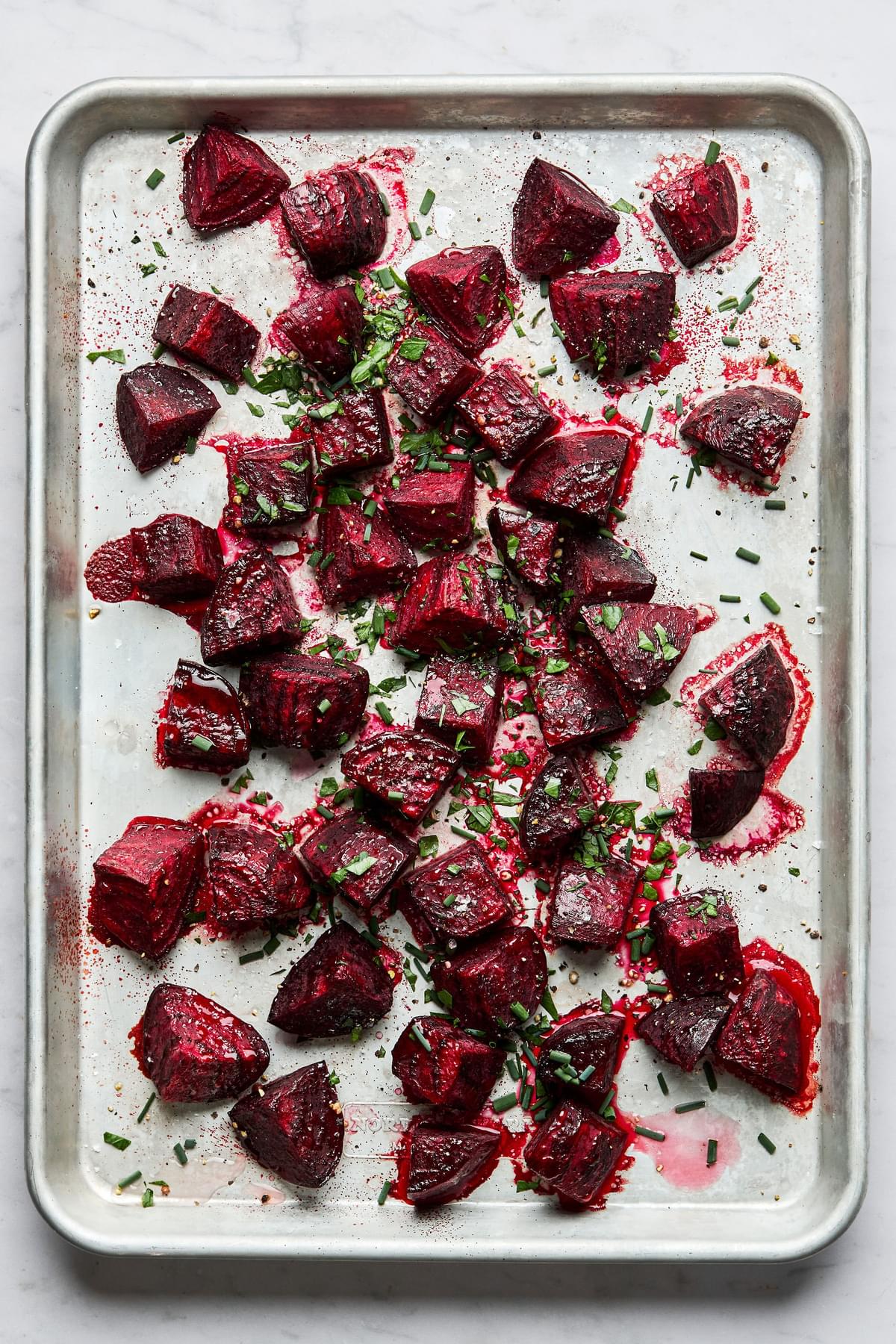 roasted beets on a baking sheet tossed with white vinegar, fresh herbs and pepper