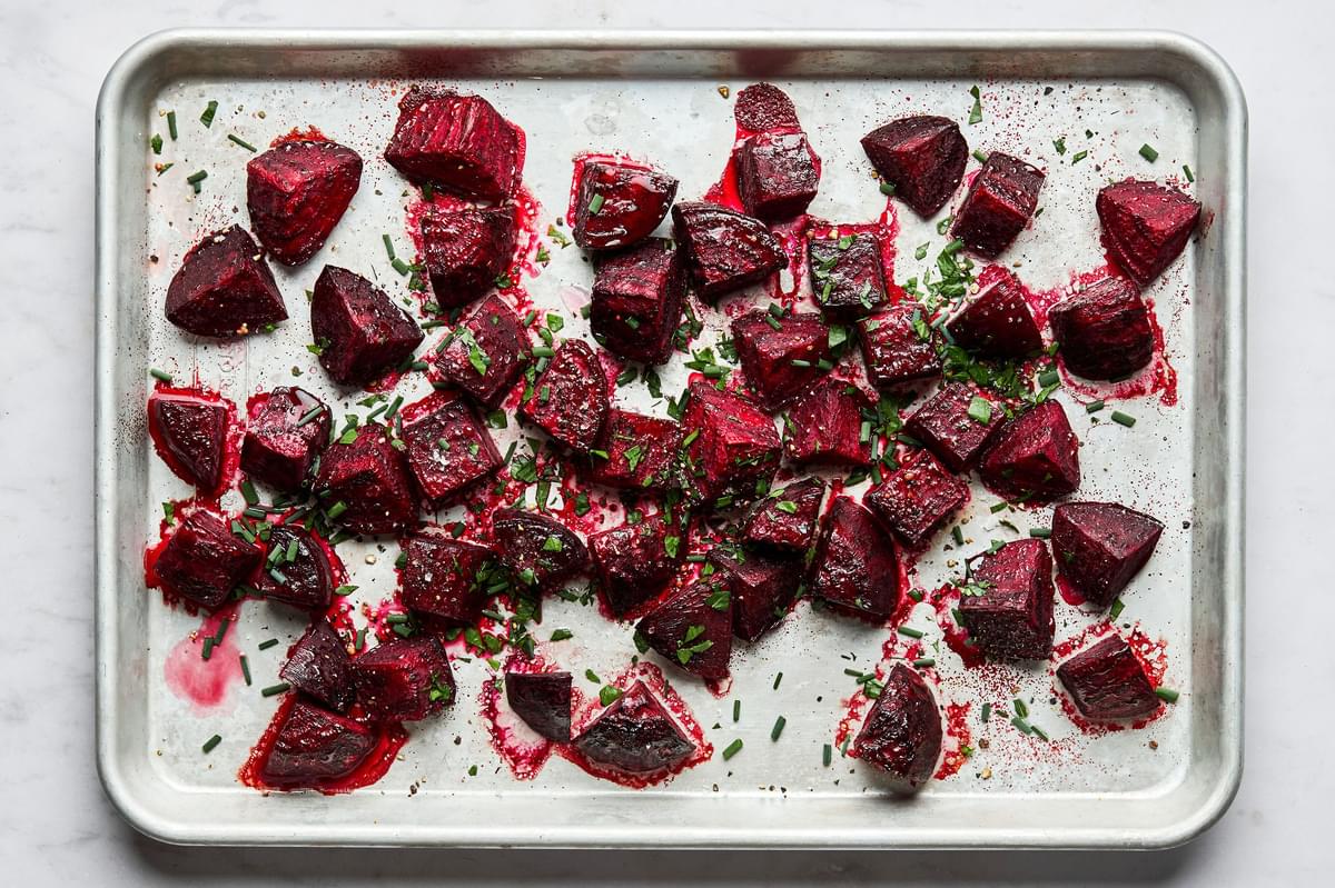 roasted beets on a baking sheet tossed with white vinegar, fresh herbs and pepper