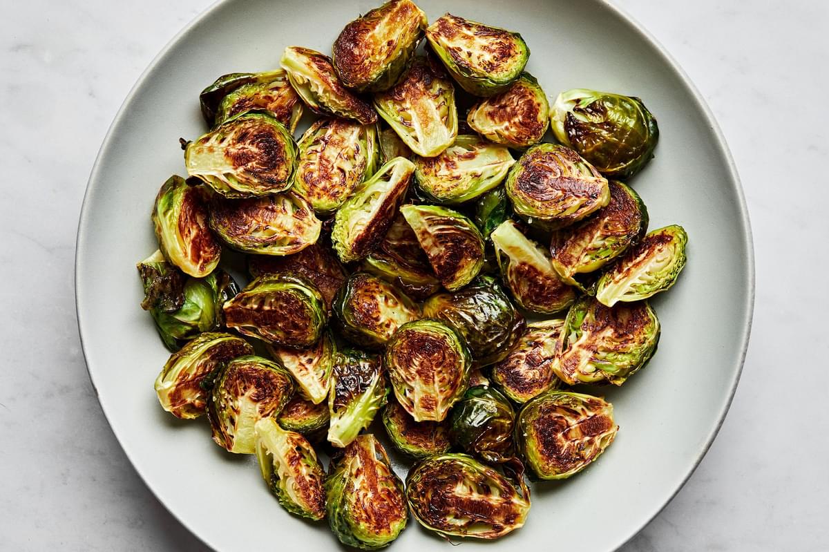 roasted Brussels sprouts in a serving bowl with caramelized, crunchy outsides seasoned with olive oil and salt