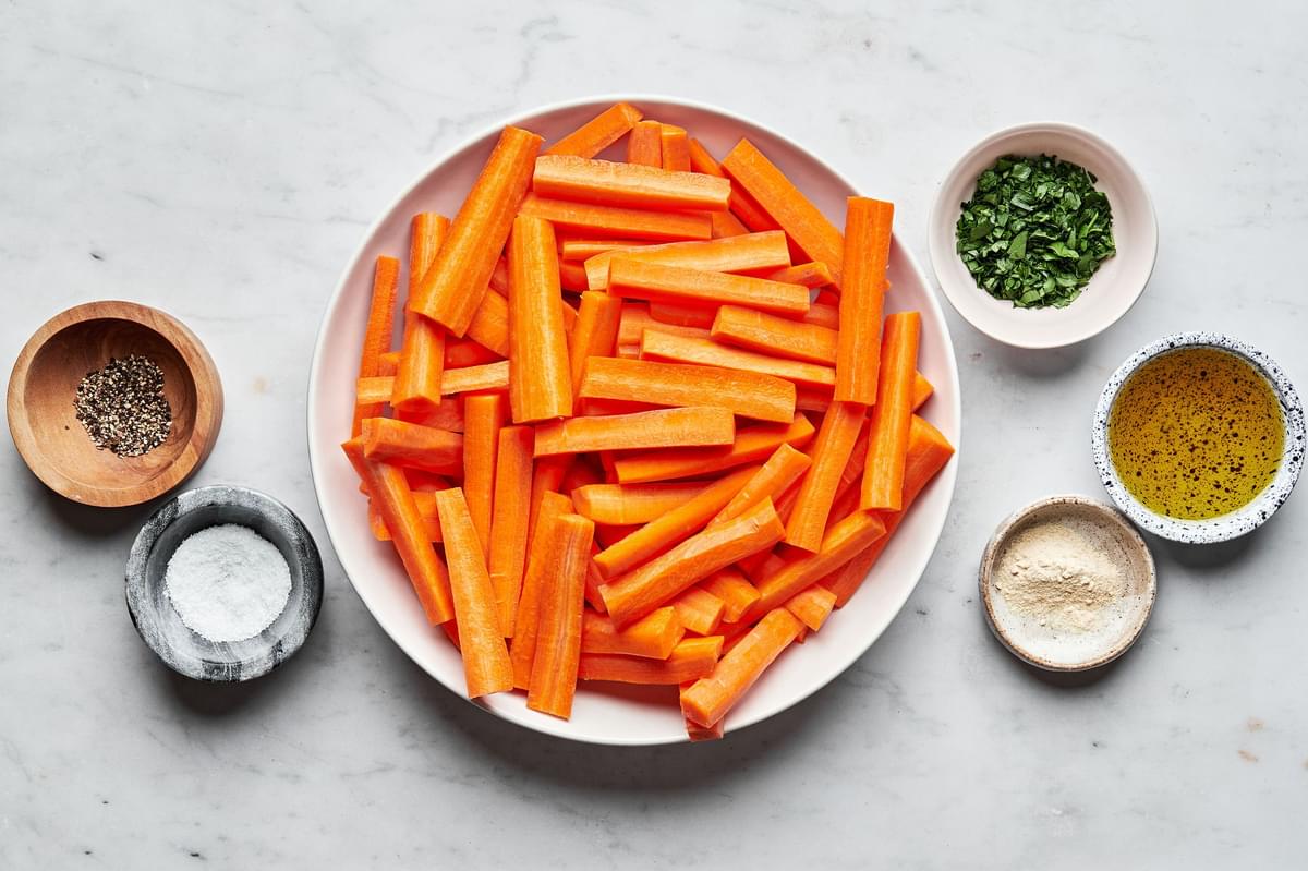 carrots, olive oil, salt, pepper, garlic powder and parsley in bowls to make roasted carrots