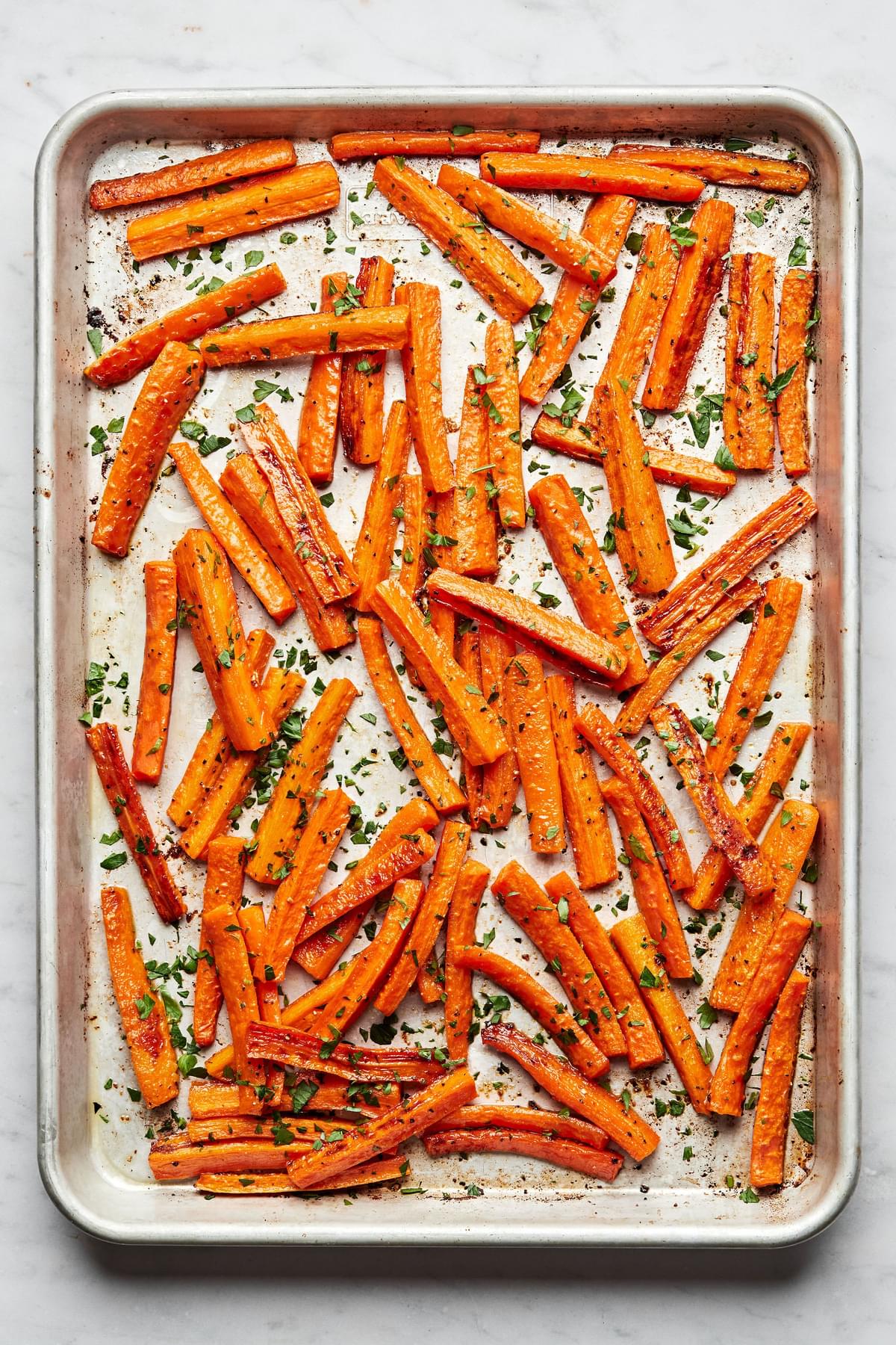 roasted carrots on a baking sheet seasoned with salt, pepper and garlic powder sprinkled with parsley