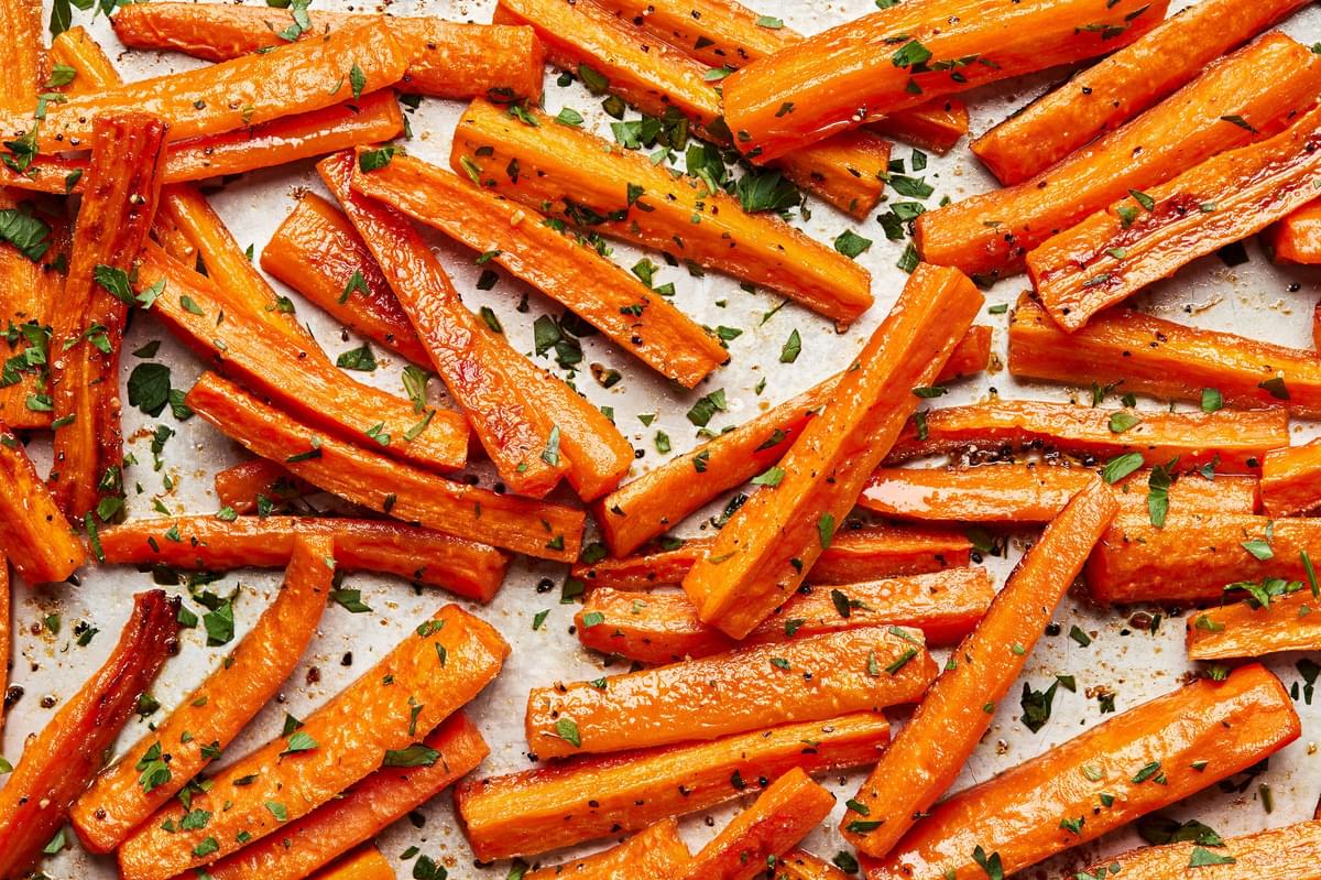 roasted carrots on a baking sheet seasoned with salt, pepper and garlic powder sprinkled with parsley