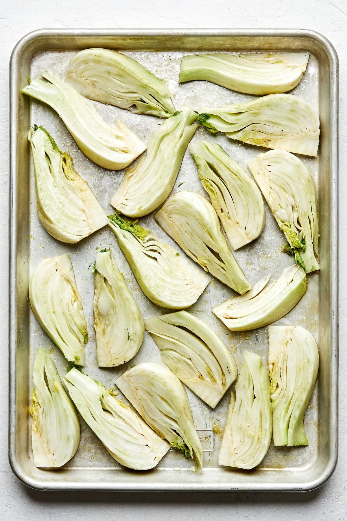raw fennel sliced on a baking sheet tossed with olive oil, salt, garlic powder and pepper