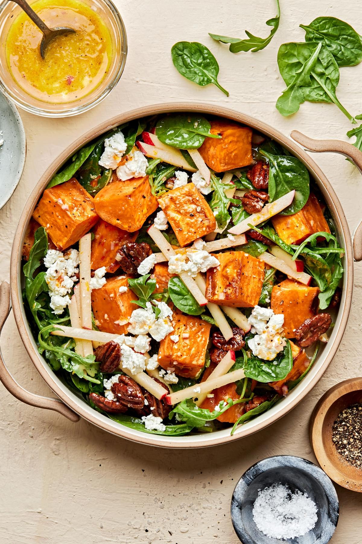 Roasted Sweet Potato Salad with Orange Vinaigrette surrounded by bowls of extra vinaigrette and salt and pepper