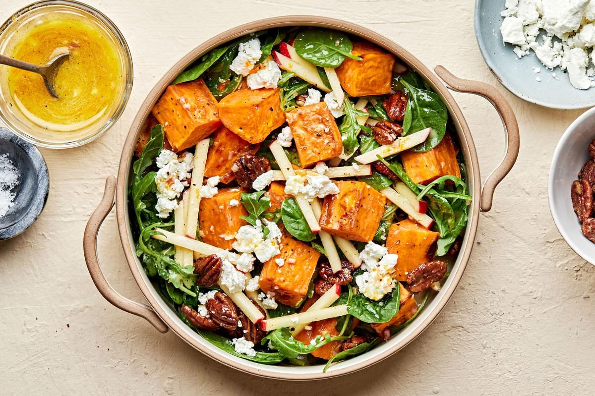 Roasted Sweet Potato Salad with Orange Vinaigrette surrounded by bowls of extra vinaigrette and goat cheese