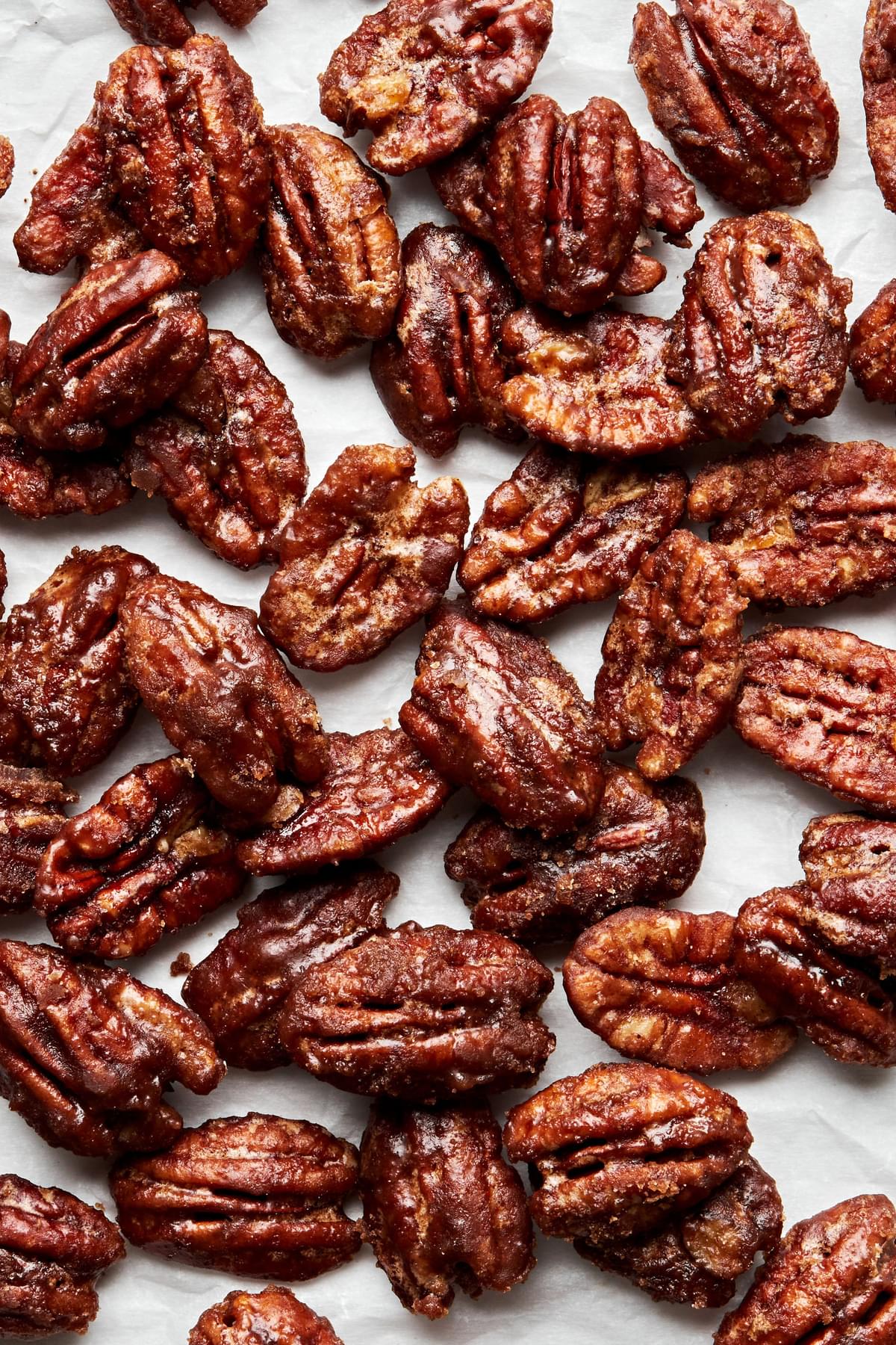 homemade candied pecans cooling on a piece of parchment paper made with brown sugar, cinnamon, cayenne and salt