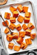 roasted sweet potatoes seasoned with olive oil, garlic powder, salt & pepper on a parchment lined baking sheet