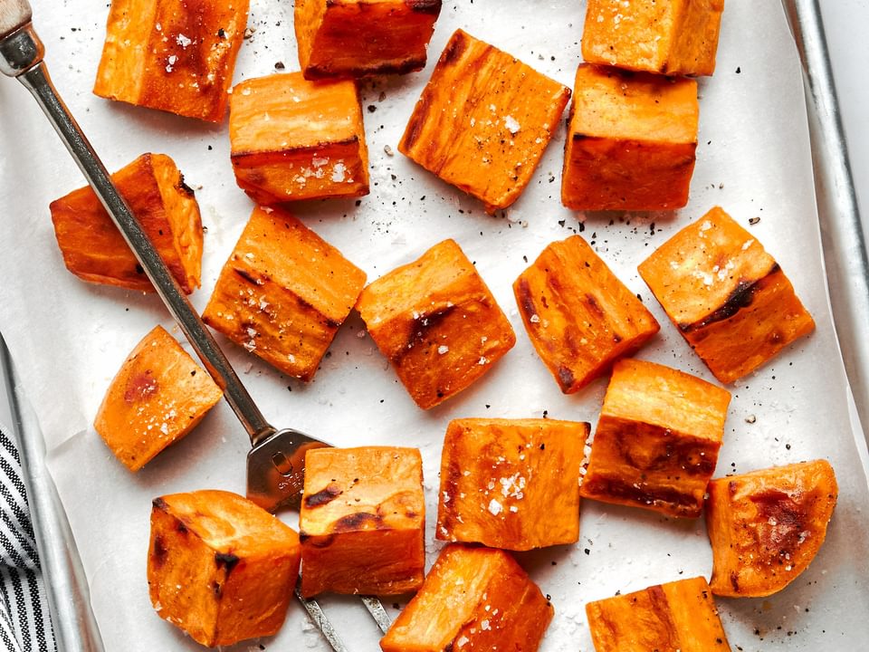 roasted sweet potatoes seasoned with olive oil, garlic powder, salt & pepper on a parchment lined baking sheet