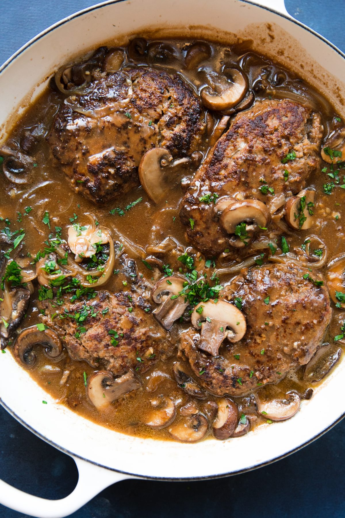 homemade Salisbury steak and gravy with mushrooms in a pot topped with fresh parsley