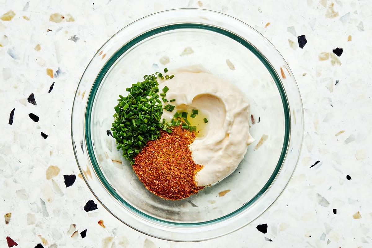 mayonnaise, chives, Old Bay Seasoning and Lemon juice in a glass bowl to make old bay mayonnaise for salmon burgers