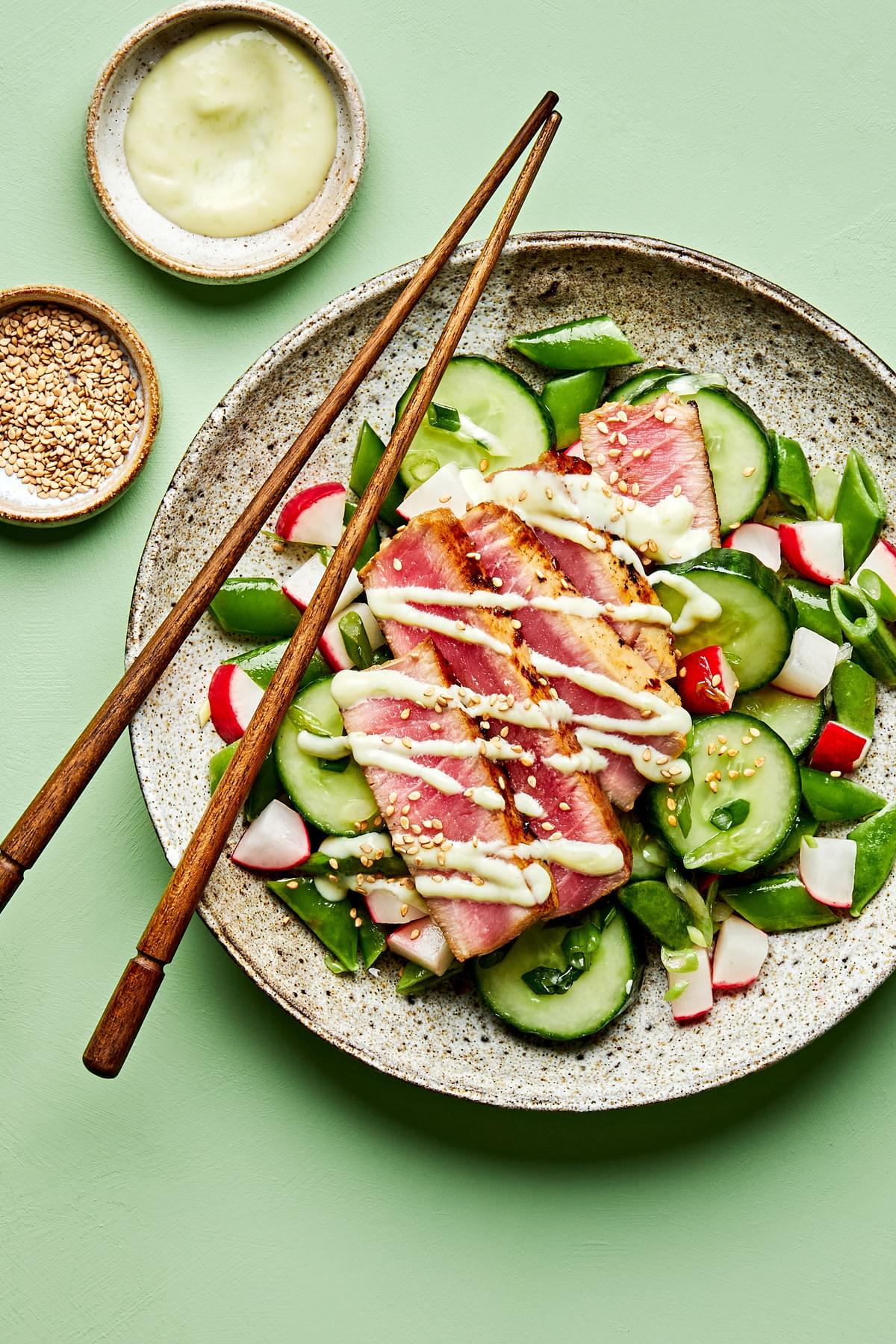 seared ahi tuna served on top of cucumber salad drizzled with  wasabi mayo and sprinkled with sesame seeds