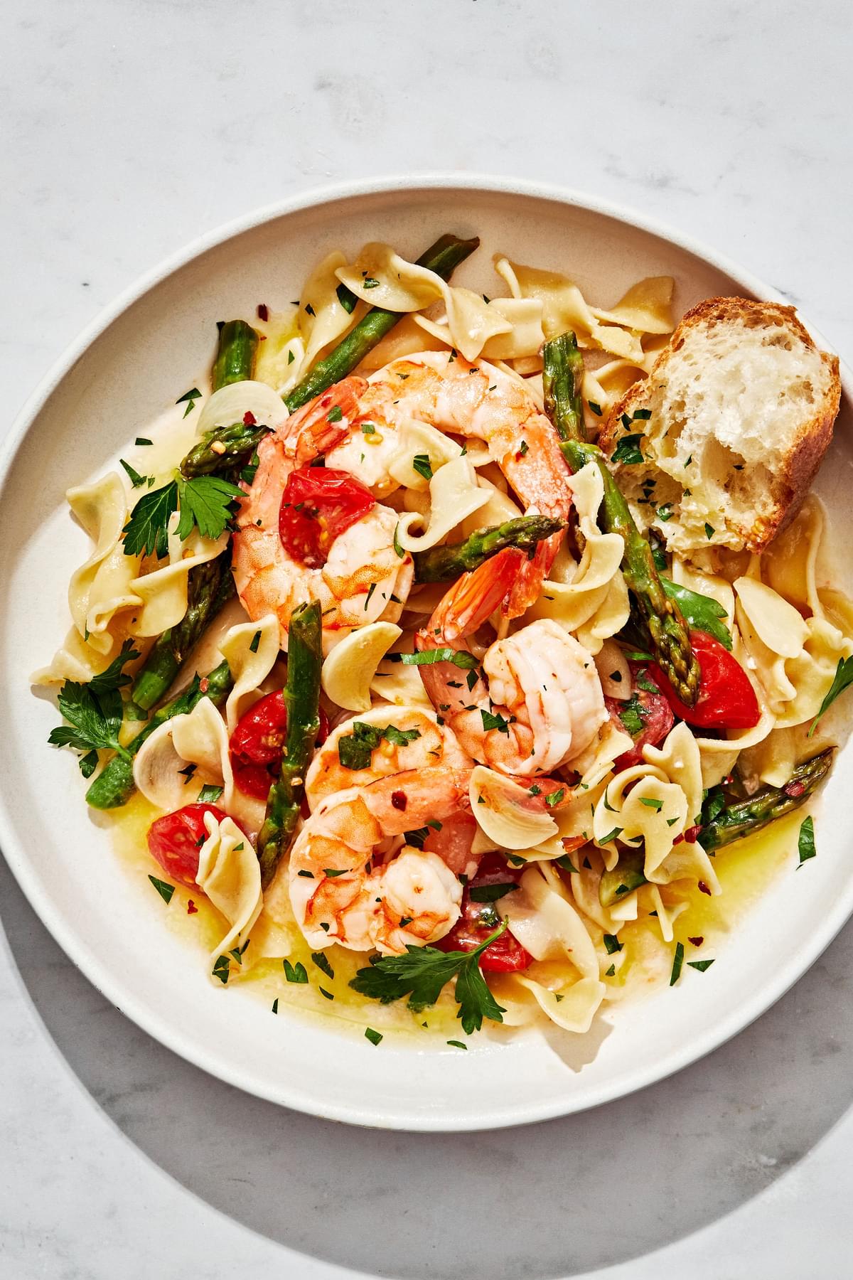 a bowl of homemade Shrimp Scampi En Papillote served over top of buttered noodles sprinkled with fresh parsley