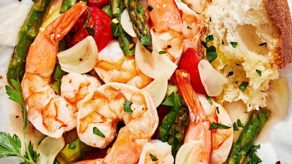 Shrimp Scampi En Papillote (in parchment) made with shrimp, asparagus, cherry tomatoes, spices and sprinkled with parsley