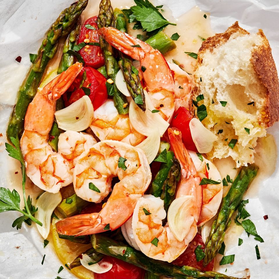 Shrimp Scampi En Papillote (in parchment) made with shrimp, asparagus, cherry tomatoes, spices and sprinkled with parsley