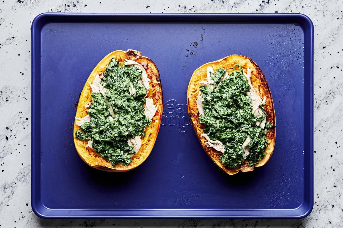 roasted spaghetti squash filled with chicken, mozzarella and creamed spinach on a baking sheet