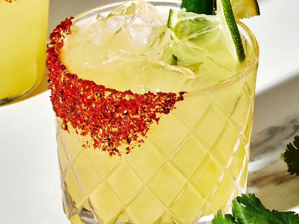 A spicy margarita with juicy lime, tequila, a hint of serrano Chile with a Tajin seasoning rim and a lime and Serrano garnish