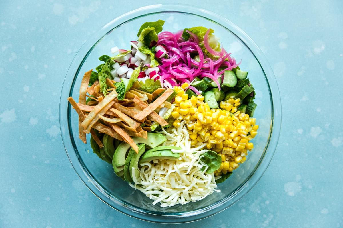 corn, Romaine, Avocado, Cucumber, Pickled onions, Radishes,Monterey Jack cheese, tortilla strips  in a bowl for tex-mex salad