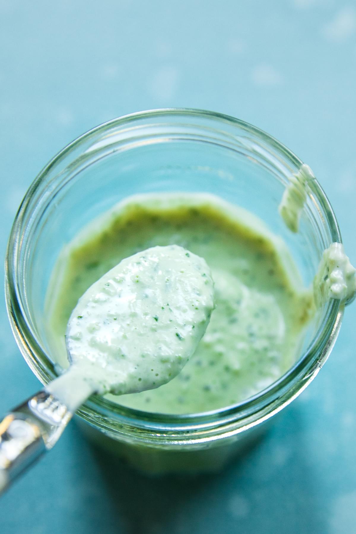 homemade creamy oregano dressing in a jar with a spoon for tex-mex salad