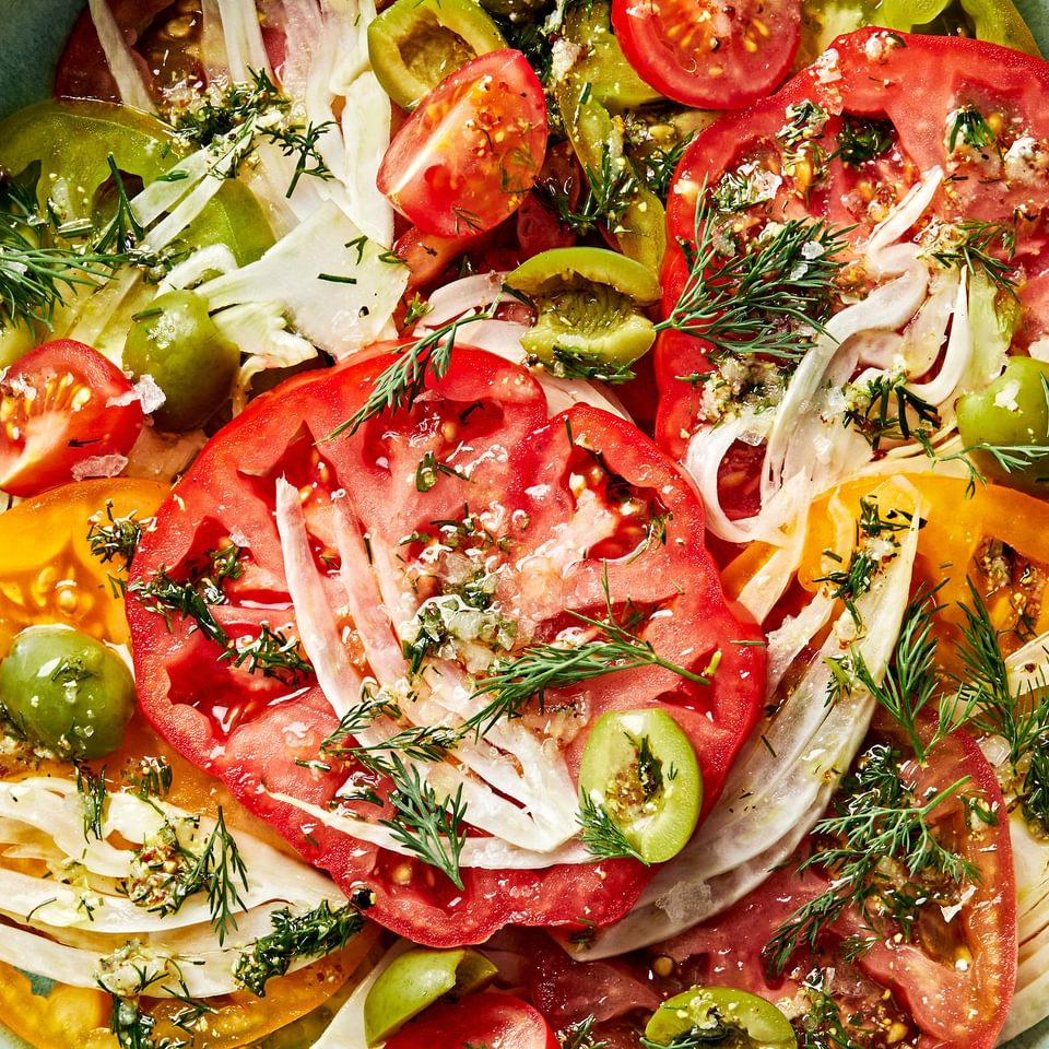 Tomato Salad made of tomatoes, fennel, olives, vinegar, garlic, dill, olive oil, stone mustard, salt & pepper in a bowl