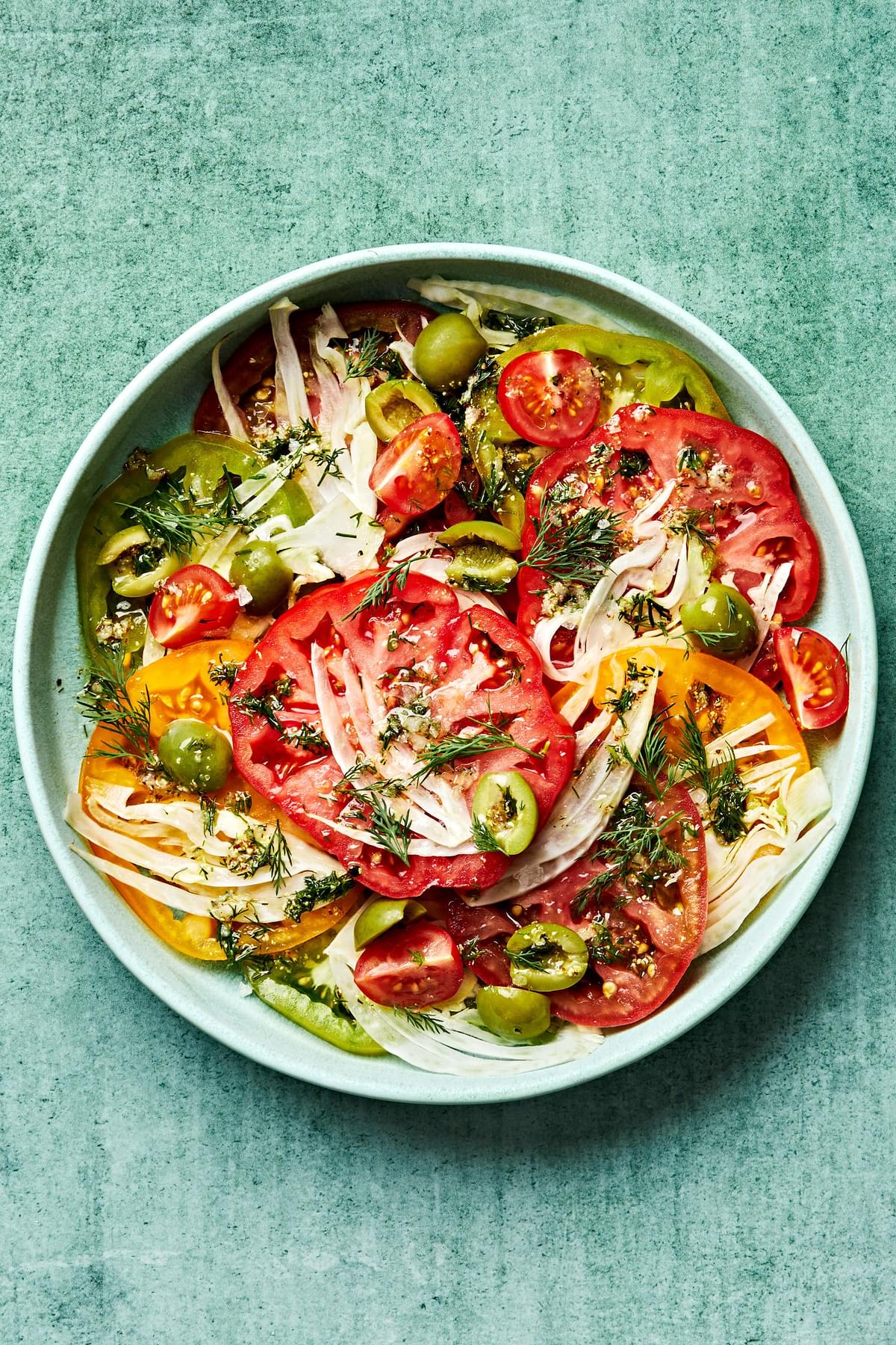 Tomato Salad in a bowl made of tomatoes, fennel, olives, vinegar, garlic, dill, olive oil, stone mustard, salt & pepper