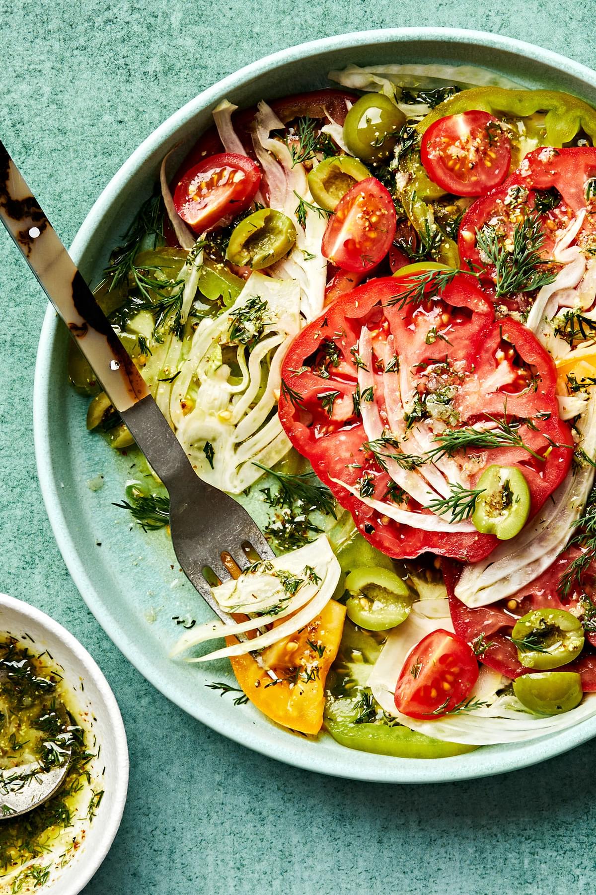 the Best Tomato Salad in a bowl with a fork made with tomatoes, fennel, olives and fresh dill