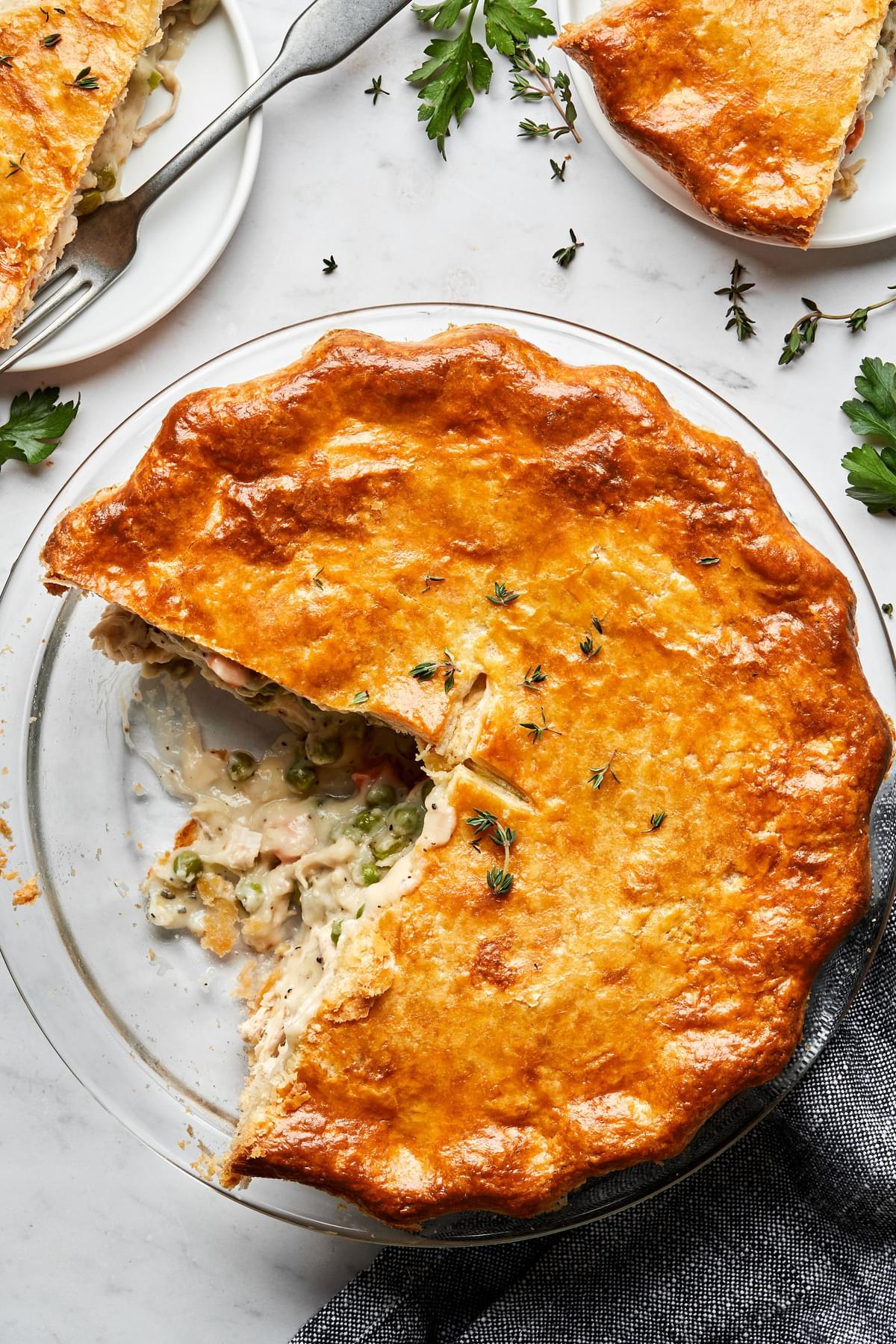 a homemade turkey pot pie filled with turkey, celery, carrot, onion & peas with a slice cut out