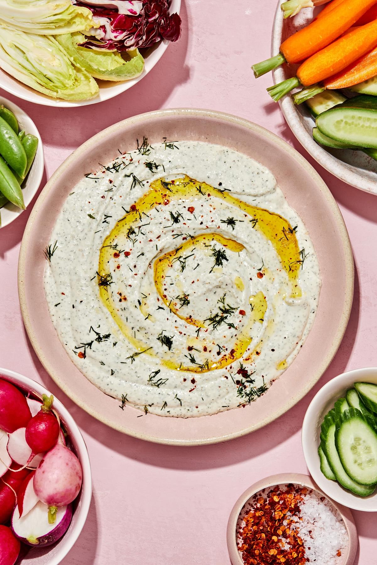 whipped feta dip made with feta, greek yogurt and spices in a serving bowl surrounded by raw vegetables for dipping