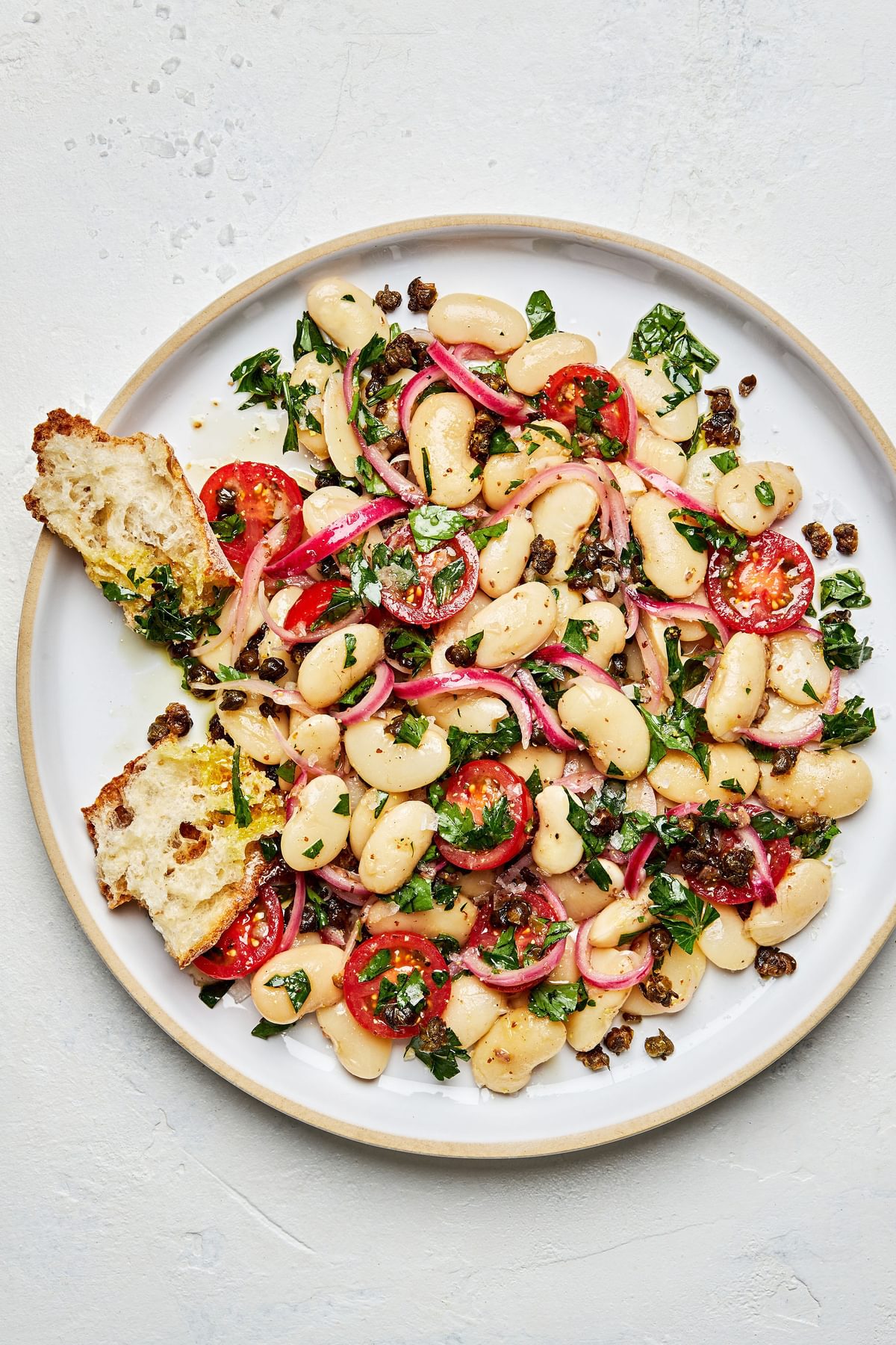 homemade white bean salad with anchovy vinaigrette on a plate served with crusty bread