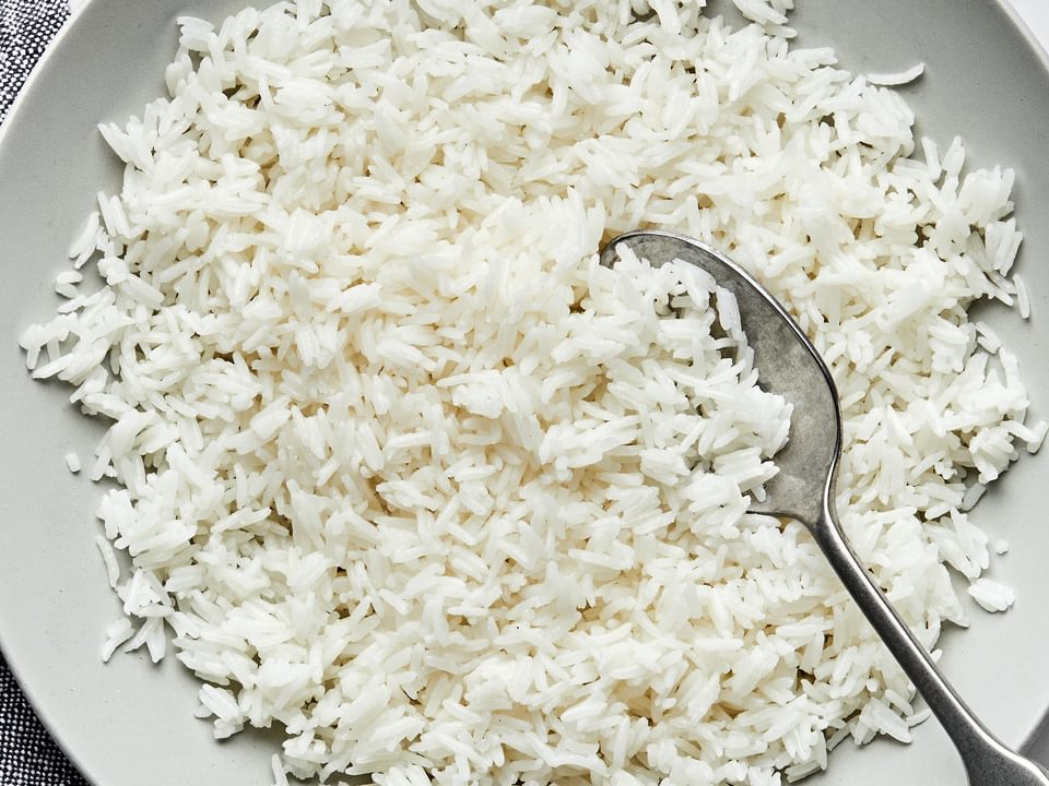 homemade fluffy white rice in a serving bowl with a spoon