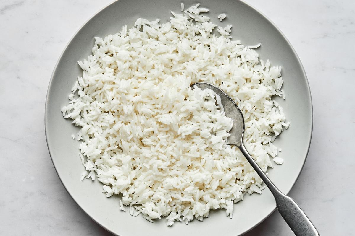 homemade fluffy white rice in a serving bowl with a spoon
