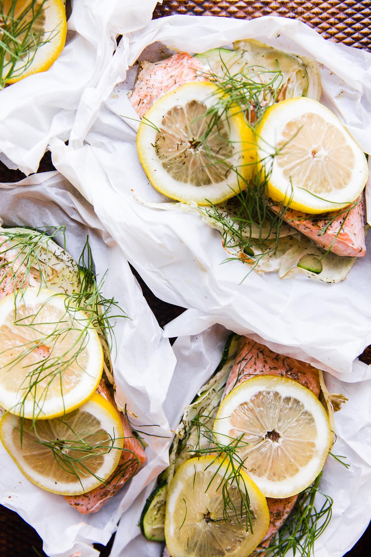 close up of salmon in parchment paper pouches opened and topped with lemon and fennel lemon