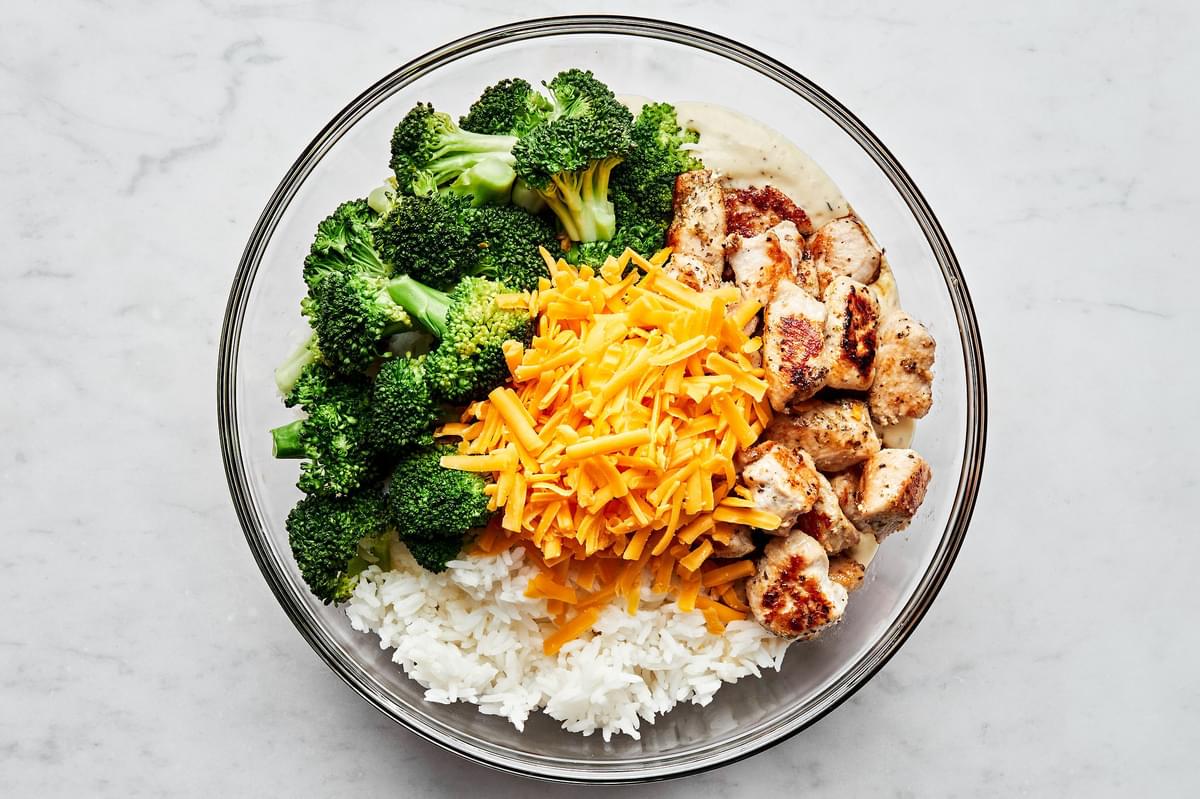 rice, broccoli, chicken and cheese in a glass bowl