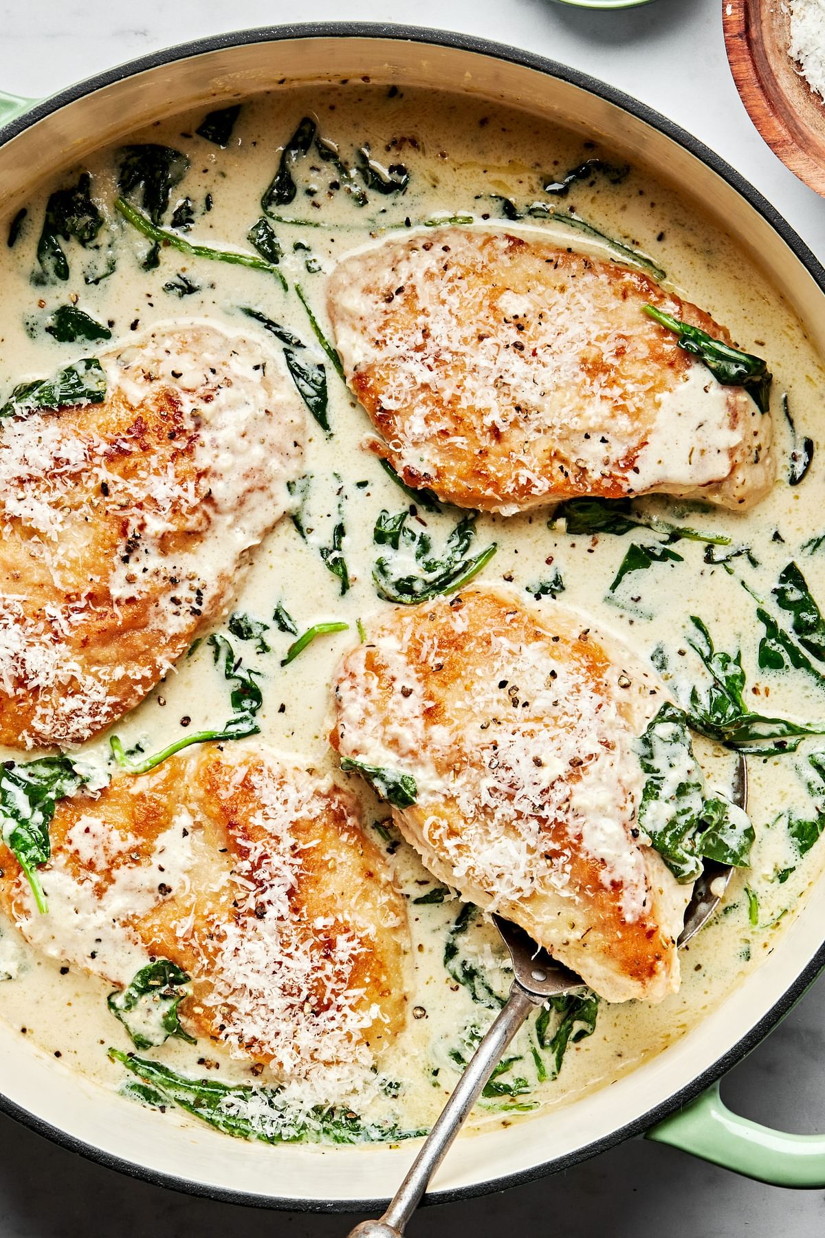 chicken florentine with cooked spinach in a rich white wine cream sauce in a skillet