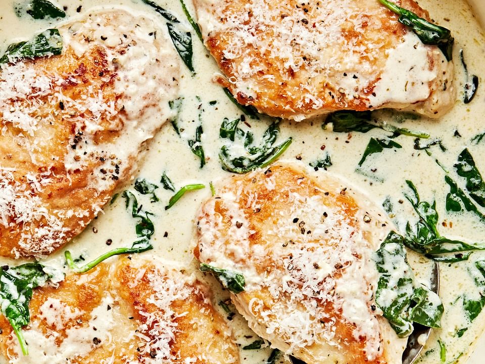 chicken florentine with cooked spinach in a rich white wine cream sauce in a skillet