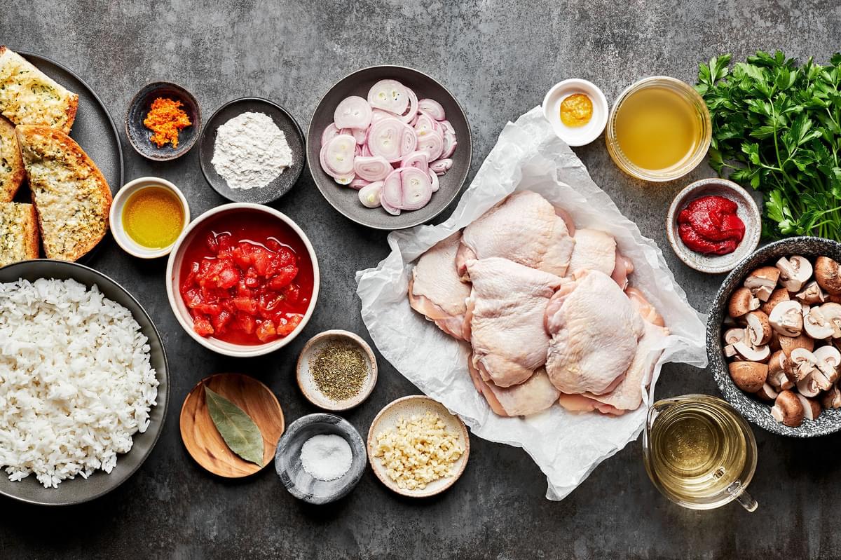ingredients for chicken marengo in prep bowls: bone-in, skin-on chicken thighs, mushrooms, shallots, diced tomatoes & spices