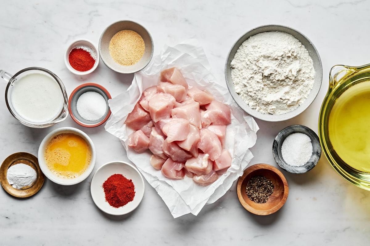 ingredients for chicken nuggets in prep bowls: chicken, flour, eggs, buttermilk, sugar, spices and vegetable oil