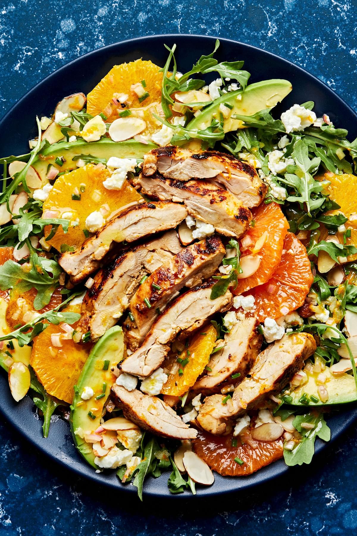 arugula drizzled with citrus dressing topped with chicken, avocado, feta, orange, almonds and chives