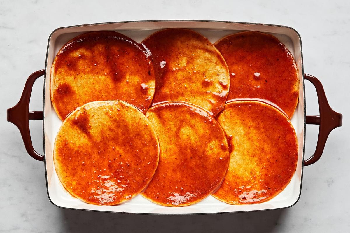 corn tortillas dipped in homemade enchilada sauce laid in the bottom of a 9x13 casserole dish