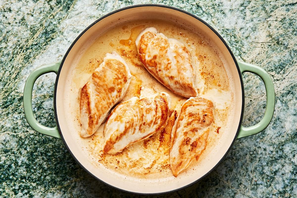 chicken being browned in olive oil in a skillet