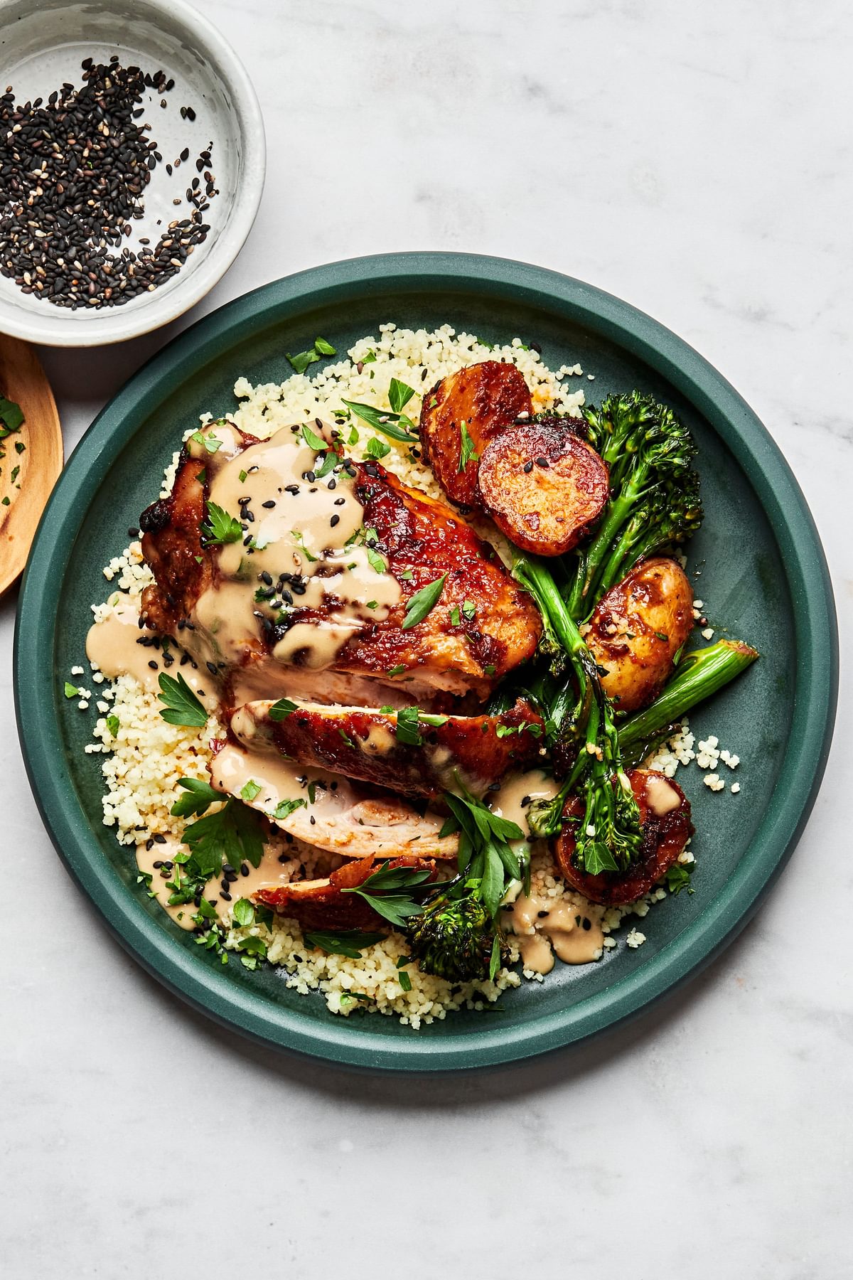 Honey harissa chicken, potatoes and broccoli served over couscous and drizzled with tahini sauce